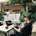Seorang Pria duduk sambil bekerja ditemani di meja minuman kopi di Kopi Subang beralamat di Kopi Qyanda